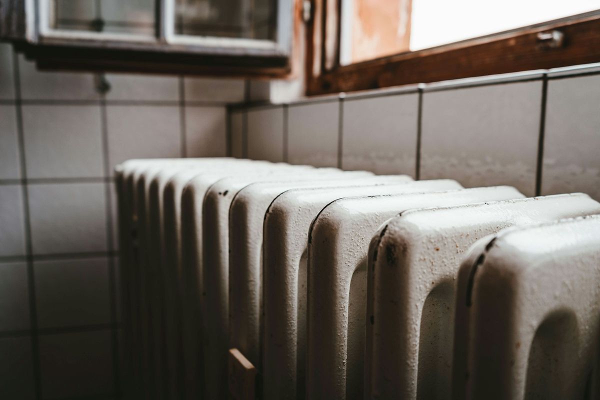 Een oude gietijzeren radiator onder een raam